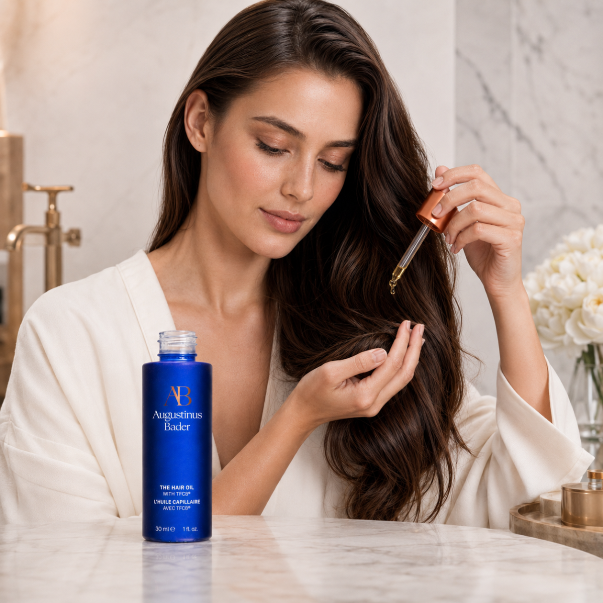 Woman applying hair oil to her hair in a bathroom setting with blue bottle on table