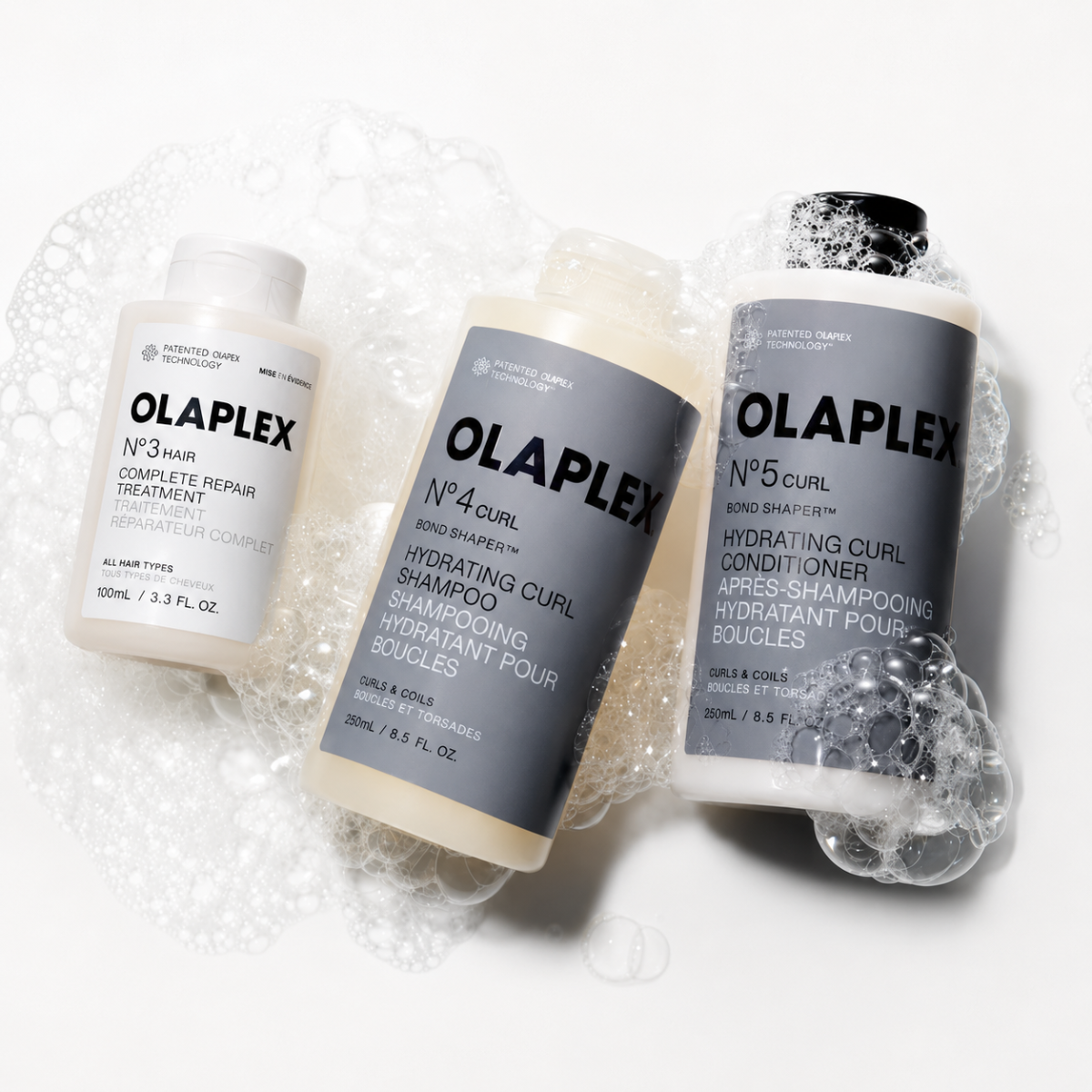 Three Olaplex hair care products on a white background with bubbles.
